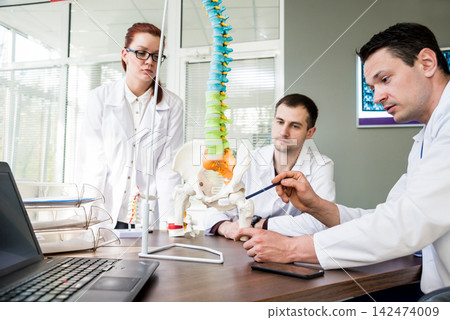 Doctors team having medical council in hospital. Discussing medical issues. Spine fixation systems Doctors team having medical council in hospital. Discussing medical issues. Spine fixation systems 142474009