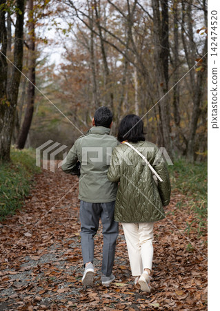 一對中年夫婦漫步在八嶽山腳下的秋葉林中。 一對中年夫婦漫步在八嶽山腳下的秋葉林中。 142474520