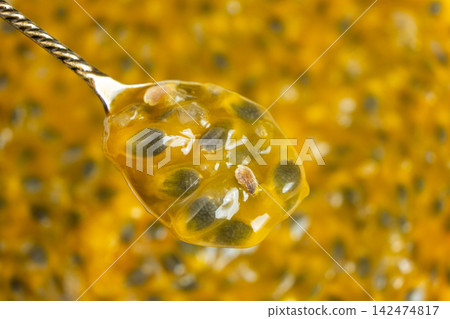 Overhead view of spoonful of ripe passionfruit pulp isolated over textured pulp backdrop Overhead view of spoonful of ripe passionfruit pulp isolated over textured pulp backdrop 142474817