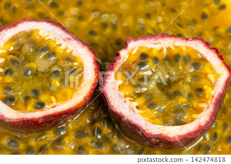 Fresh halved passion fruit with purple skin on bright yellow pulp backdrop Fresh halved passion fruit with purple skin on bright yellow pulp backdrop 142474818