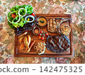 Grilled Tomahawk and Ribeye Steak Platter with Potato Wedges and Salad 142475325