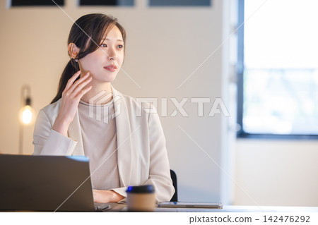 辦公室裡,一位女商務人士一手托著下巴,一邊看著筆電,一邊思考著各種想法。 辦公室裡,一位女商務人士一手托著下巴,一邊看著筆電,一邊思考著各種想法。 142476292