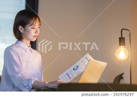 一位女商務人士正在辦公室閱讀文件上的資料。 一位女商務人士正在辦公室閱讀文件上的資料。 142476297