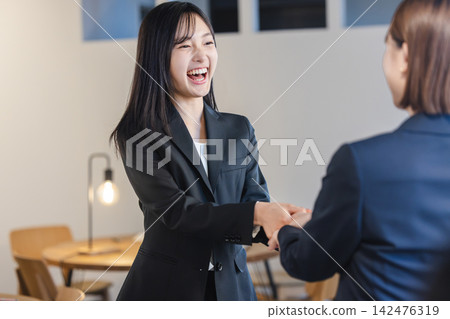 The female employee shakes hands with a beaming smile, overjoyed. The female employee shakes hands with a beaming smile, overjoyed. 142476319