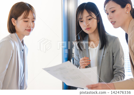 A female business person reviewing documents during a meeting. A female business person reviewing documents during a meeting. 142476336