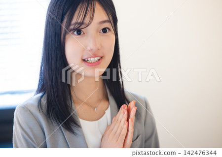 一位年輕的女員工面帶微笑,雙手合十,似乎對這個解釋感到滿意。 一位年輕的女員工面帶微笑,雙手合十,似乎對這個解釋感到滿意。 142476344