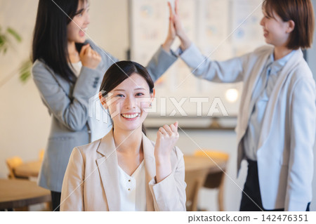 一名女員工面帶微笑,揮舞著拳頭,慶祝團隊的成功。 一名女員工面帶微笑,揮舞著拳頭,慶祝團隊的成功。 142476351