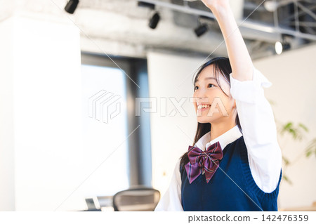 身穿校服的女學生在課堂或講座中熱情地舉手。 142476359