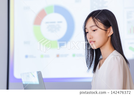 一位女性商務人士使用筆記型電腦進行演示,背景顯示分析數據。 一位女性商務人士使用筆記型電腦進行演示,背景顯示分析數據。 142476372