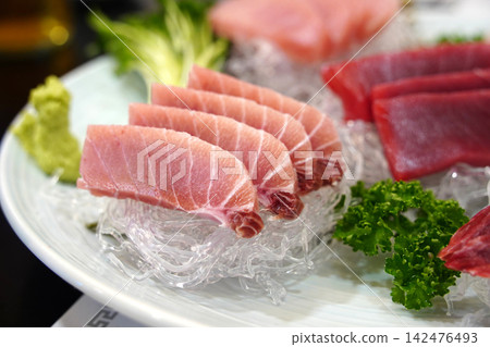 Elegant Presentation of Fresh Red Tuna Sashimi Slices on White Decorative Strands 142476493