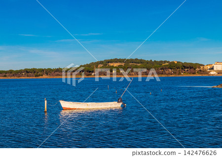 Traditional vintage wooden fishing boat moored in the calm lagoon of Etang de Gruissan in Occitanie, South of France Traditional vintage wooden fishing boat moored in the calm lagoon of Etang de Gruissan in Occitanie, South of France 142476626