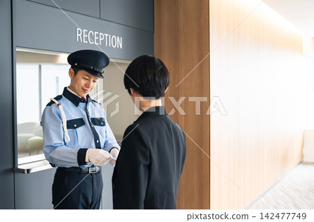 一名女子向保安出示一張卡片。身分證、身分識別卡、員工證、門禁卡、票券、犯罪預防、保全、身分驗證。 142477749