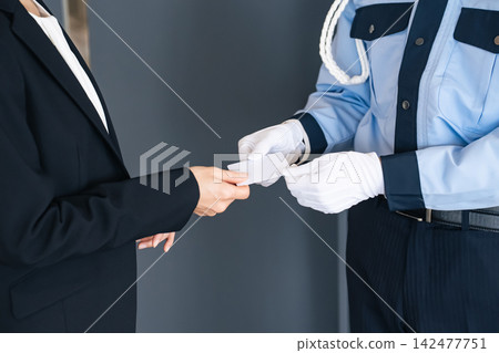 一名女子向保安出示一張卡片。身分證、身分識別卡、員工證、門禁卡、票券、犯罪預防、保全、身分驗證。 一名女子向保安出示一張卡片。身分證、身分識別卡、員工證、門禁卡、票券、犯罪預防、保全、身分驗證。 142477751