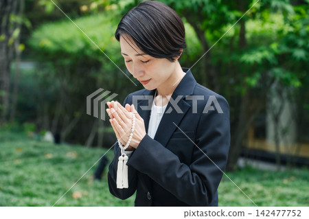 一位身著喪服的女子雙手合十祈禱。墓園、祭掃、追思會、喪服、葬禮、殯儀館、樹葬、公墓 一位身著喪服的女子雙手合十祈禱。墓園、祭掃、追思會、喪服、葬禮、殯儀館、樹葬、公墓 142477752
