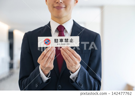 一名男子手持禁止停車標誌。司機、駕駛、規則、條例、限制、停車場、指導、方向、指示、交通、道路 一名男子手持禁止停車標誌。司機、駕駛、規則、條例、限制、停車場、指導、方向、指示、交通、道路 142477762