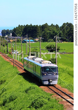 A former Seibu New Red Arrow (20020 series) train running through the lush greenery of the Toyama Chihō Railway Tateyama Line, a three-car train captured in a vertical telephoto shot. A former Seibu New Red Arrow (20020 series) train running through the lush greenery of the Toyama Chihō Railway Tateyama Line, a three-car train captured in a vertical telephoto shot. 142477958