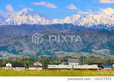 A former Seibu Red Arrow (16010 series) of the Toyama Chihō Railway, running against the backdrop of the majestic Mt. Tsurugi and the Northern Alps, captured with a telephoto lens. A former Seibu Red Arrow (16010 series) of the Toyama Chihō Railway, running against the backdrop of the majestic Mt. Tsurugi and the Northern Alps, captured with a telephoto lens. 142477978