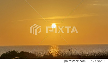 Bright Orange Sunrise View Over the Beach Grass and Ocean in Corolla North Carolina Bright Orange Sunrise View Over the Beach Grass and Ocean in Corolla North Carolina 142478216