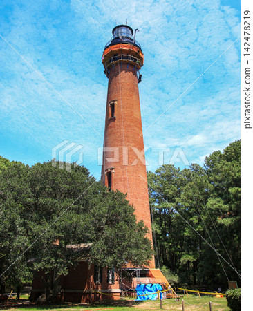 Currituck Beach Lighthouse Stands Tall Under a Bright Blue Sky 142478219