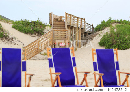 Beach Access over Sand Dunes in Corolla North Carolina With Empty Chairs in View Beach Access over Sand Dunes in Corolla North Carolina With Empty Chairs in View 142478242