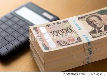 一疊500萬日元鈔票和一個計算器 一疊500萬日元鈔票和一個計算器 142478349