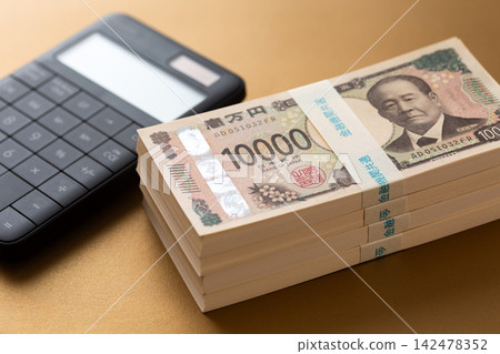 一疊400萬日元鈔票和一個計算器 一疊400萬日元鈔票和一個計算器 142478352