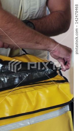 Vertical video. Close up woman opens door to food delivery man taking order out of thermal insulated bag and giving it to female customer. View from the apartment. Inside shot. Food delivery concept. Vertical video. Close up woman opens door to food delivery man taking order out of thermal insulated bag and giving it to female customer. View from the apartment. Inside shot. Food delivery concept. 142478468