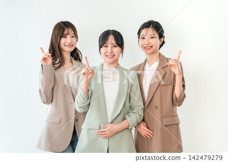三位年輕的亞洲女商人面帶微笑，指著一個點。 142479279