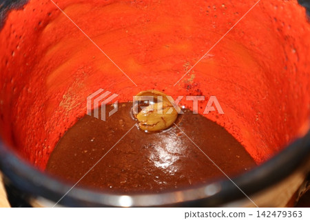 Mixing chocolate in a clay pot during a festival in Mexico Mixing chocolate in a clay pot during a festival in Mexico 142479363