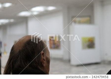 Visitor looks at paintings in an art gallery. Visitor looks at paintings in an art gallery. 142479458