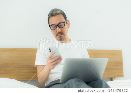 一個人在床上看電腦 一個人在床上看電腦 142479822