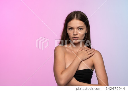 Young woman applying under eye patches for skincare routine, creating a beauty and wellness concept Young woman applying under eye patches for skincare routine, creating a beauty and wellness concept 142479944