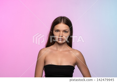 Young woman applying under eye patches for skin care routine, practicing beauty and self-care on gradient background Young woman applying under eye patches for skin care routine, practicing beauty and self-care on gradient background 142479945