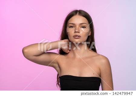 Young woman applying under eye patches, performing a self-care beauty routine for hydrated and healthy skin Young woman applying under eye patches, performing a self-care beauty routine for hydrated and healthy skin 142479947