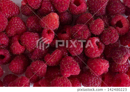 Fresh ripe raspberries filling the frame in a close-up top view. Red summer berries with natural texture and visible drupelets for food, nutrition and healthy eating concepts Fresh ripe raspberries filling the frame in a close-up top view. Red summer berries with natural texture and visible drupelets for food, nutrition and healthy eating concepts 142480223
