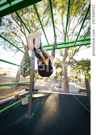 Person swings on playground equipment in a park during the day 142480452