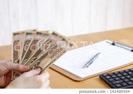 一個人手持鈔票的圖片;這是資金管理和支付的視覺表現。 一個人手持鈔票的圖片;這是資金管理和支付的視覺表現。 142480504