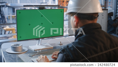 Engineer at Factory Control Desk with Green Screen Monitor in Glass Office Engineer at Factory Control Desk with Green Screen Monitor in Glass Office 142480724