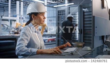 Female Technician Operating Computer Workstation near Server Rack in Plant Female Technician Operating Computer Workstation near Server Rack in Plant 142480761