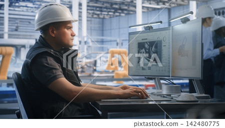 Technician Controlling Automated Robotic Assembly via Dual Screen PC Technician Controlling Automated Robotic Assembly via Dual Screen PC 142480775
