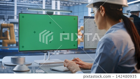 Female Engineer Working at Smart Factory Desk with Green Screen Chroma Key Monitor 142480935