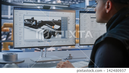 Male Operator Managing Automated Production Workflows and CAD Blueprints on Dual Screens 142480937