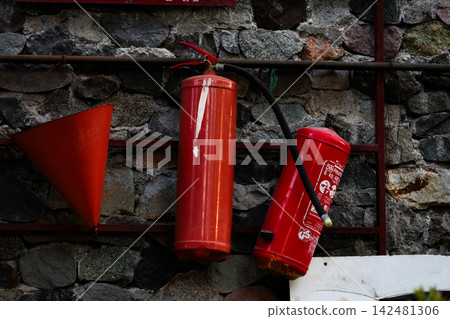 Red Fire Extinguishers Mounted on Stone Wall Red Fire Extinguishers Mounted on Stone Wall 142481306