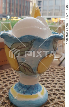 Refreshing lemon sorbet with cream in a decorative hand-painted ceramic bowl on a wicker table Refreshing lemon sorbet with cream in a decorative hand-painted ceramic bowl on a wicker table 142481386