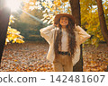 Smiling young woman in the autumn forest with the yellow leaves with sunset rays. 142481607