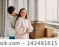 Happy young family couple man and woman hugging after moving cardboard boxes to their new apartment 142481615