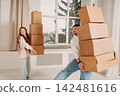 Happy young family couple man and woman moving with cardboard boxes to new estate home apartment 142481616