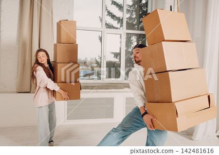 Happy young family couple man and woman moving with cardboard boxes to new estate home apartment Happy young family couple man and woman moving with cardboard boxes to new estate home apartment 142481616