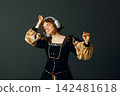 Portrait of a young aristocratic woman with headphones on her head and dressed in a medieval dress listens classical music. 142481618