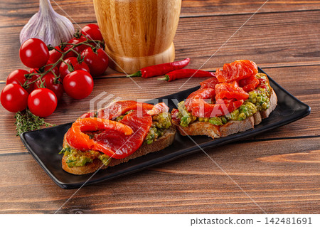 Salmon and avocado toast with fresh tomatoes and chili on rustic wooden background Salmon and avocado toast with fresh tomatoes and chili on rustic wooden background 142481691